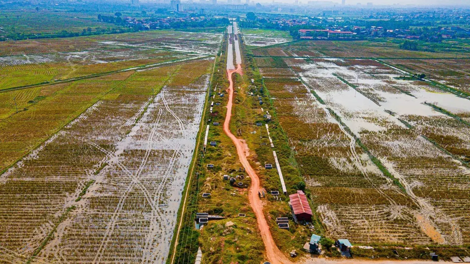 Trục đường công vụ cắt thẳng qua những thửa ruộng trên khu đất dự án, nhìn từ trên cao